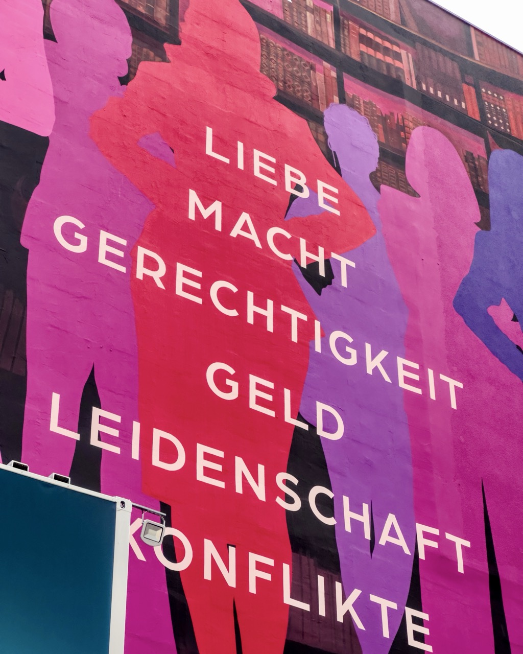 Detailaufnahme des All’s Fair Murals mit farbigen Silhouetten und zentralen Begriffen wie Liebe, Macht und Gerechtigkeit
