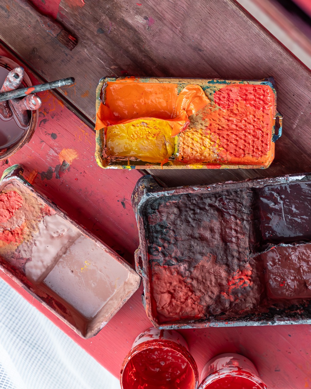 Farbwannen mit roten, orangefarbenen und gelben Farbtönen auf einer Arbeitsfläche während der Mural-Produktion