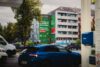 Blick von einer Tankstelle auf das großformatige S-Bahn München Mural an einer stark befahrenen Straße in München.