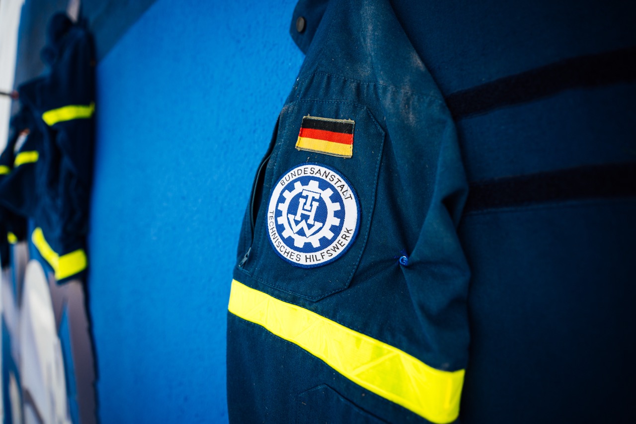 Detailaufnahme einer THW-Uniform mit Bundesflagge und Logo auf blauem Hintergrund.