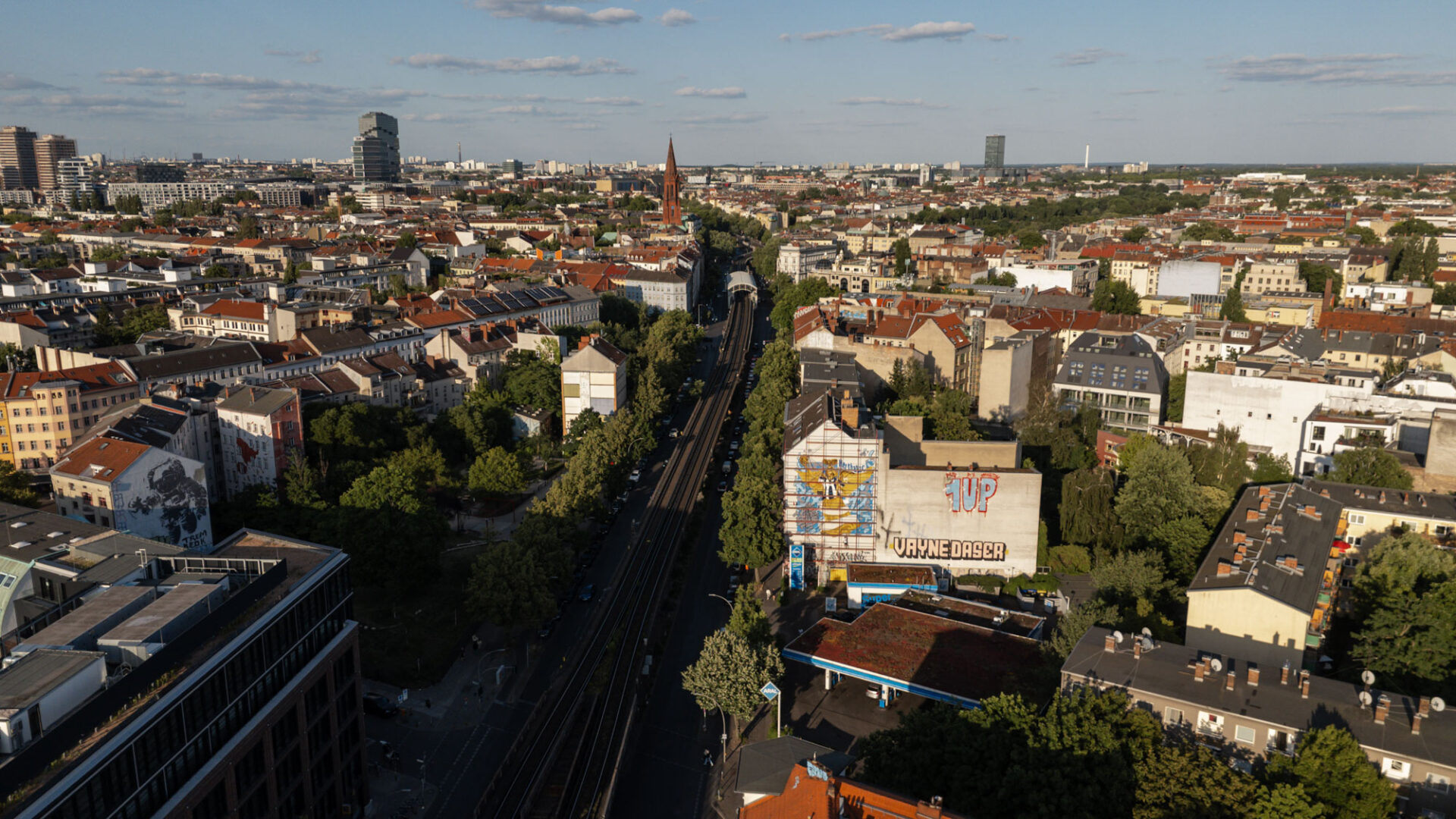 Luftaufnahme von Berlin mit Bahntrasse und einem großen Hertha-BSC-Mural an einer Gebäudefassade.