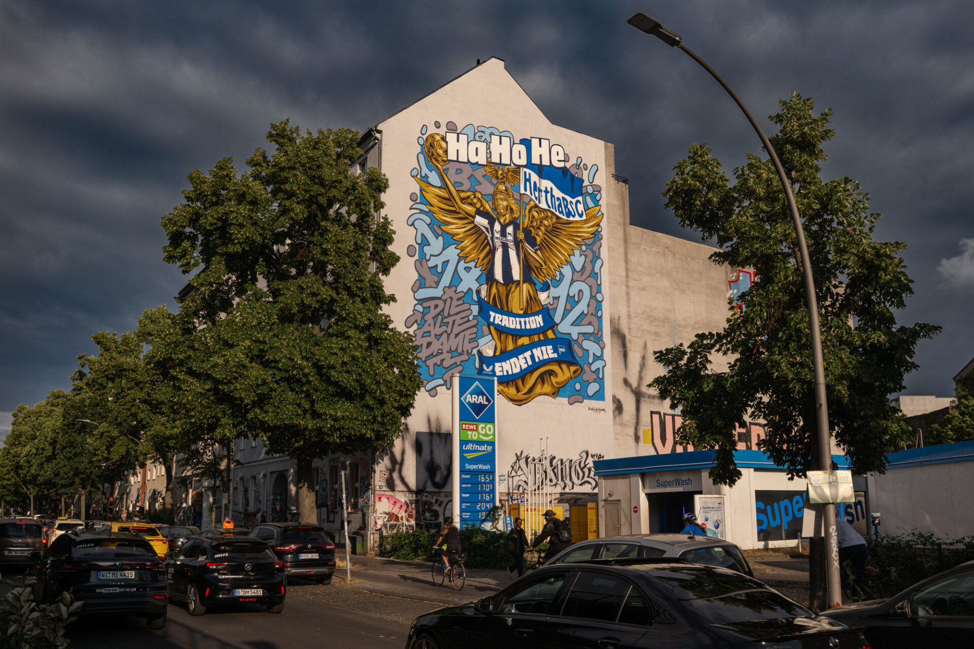 Großes Hertha-BSC-Mural an einer Berliner Hausfassade mit Verkehr auf der Straße im Vordergrund.