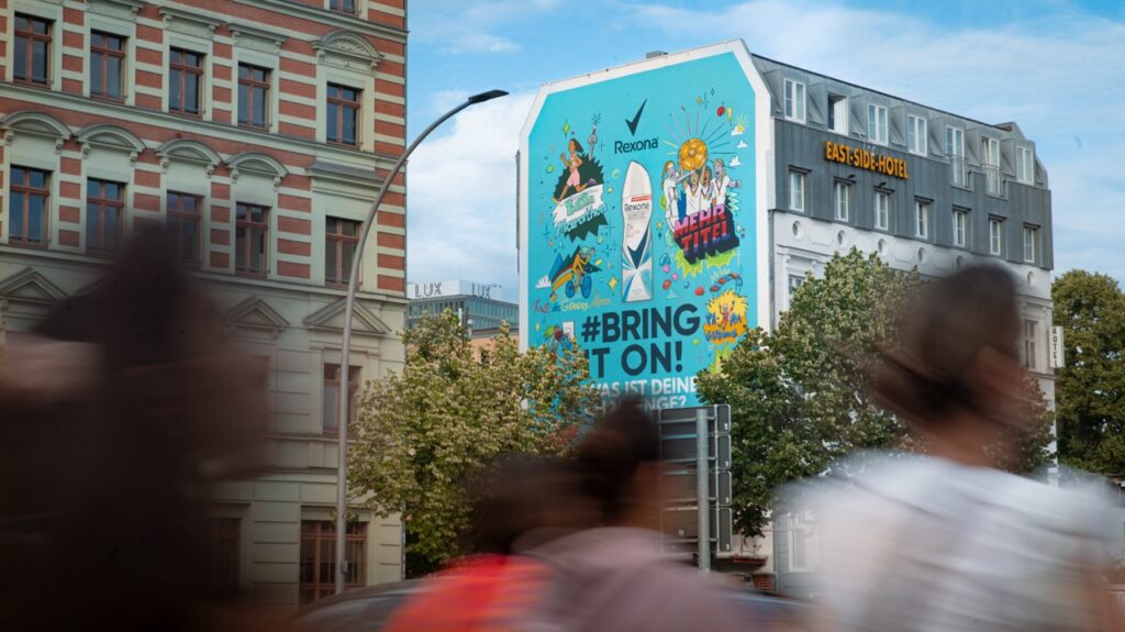 Passanten laufen vor dem großformatigen Rexona Mural nahe der East Side Gallery in Berlin vorbei.