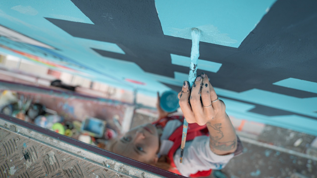 Detailaufnahme beim Malen des Rexona Murals – Pinselarbeit an der türkisfarbenen Wandfläche.