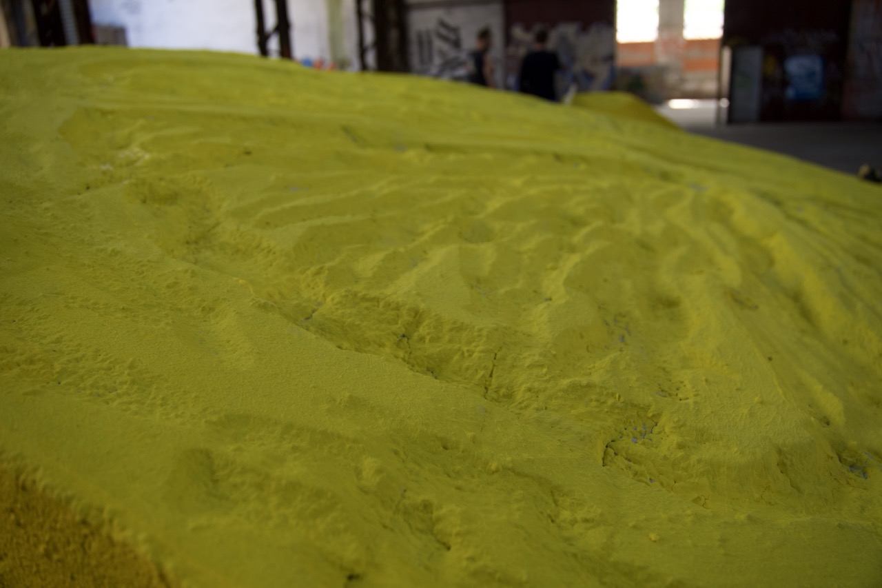 Detailaufnahme einer gelb eingefärbten, handgeformten Styroporstruktur mit unregelmäßiger Oberfläche, die an die Textur einer Zitronenschale erinnert.