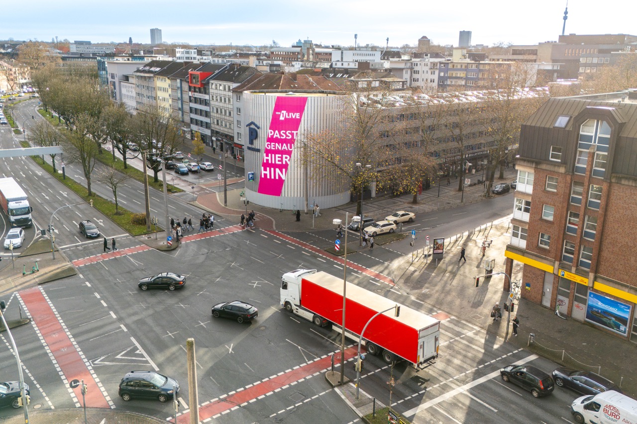 Luftaufnahme einer belebten Straßenkreuzung in Dortmund mit großflächiger 1LIVE Werbung an einem runden Parkhaus