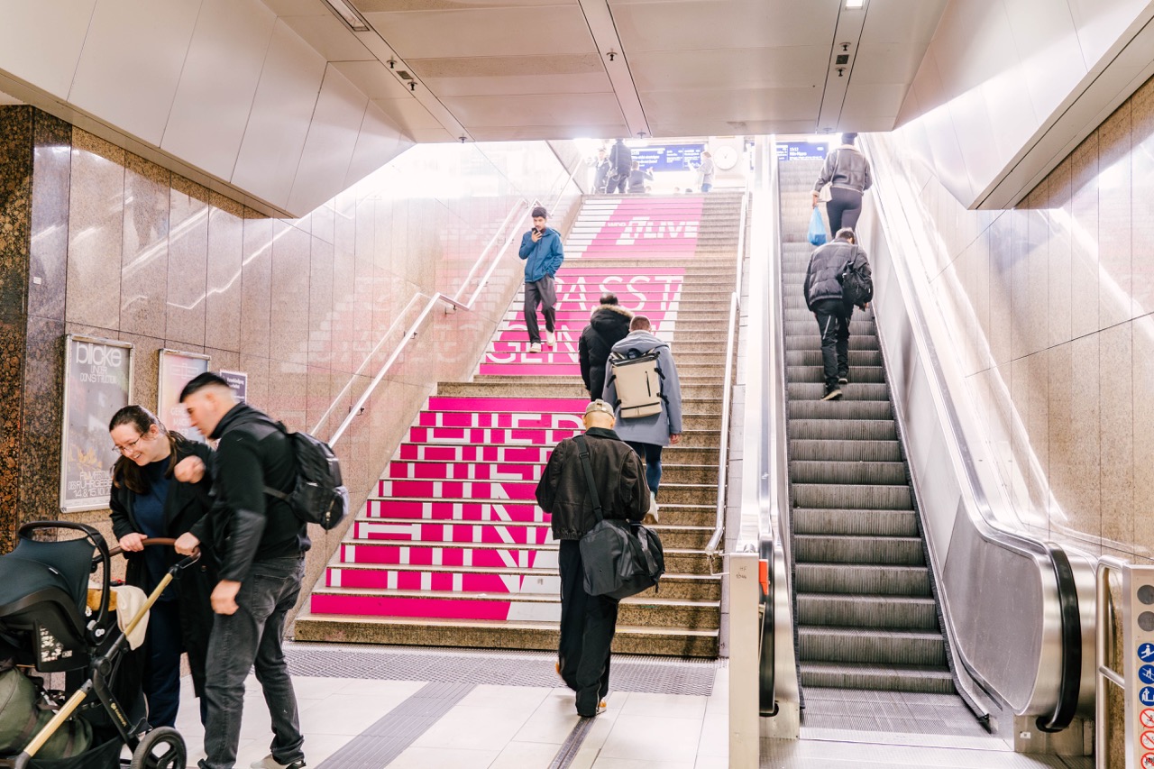 Beklebte Treppe in einer Unterführung in Düsseldorf mit 1LIVE Branding und Passanten auf dem Weg nach oben