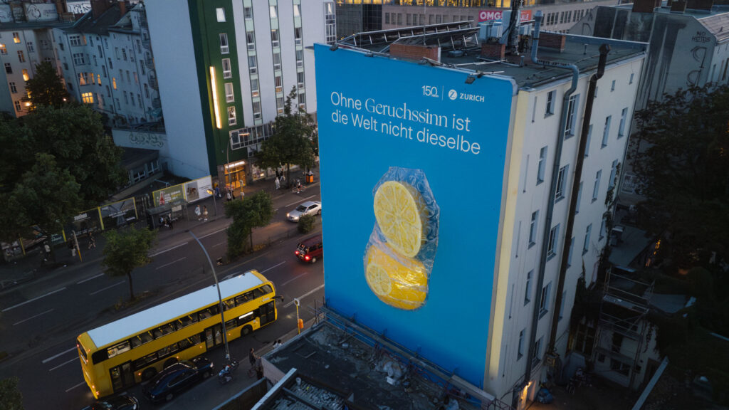Großes Fassadenmural mit zwei Zitronen und Schriftzug auf blauem Hintergrund an einem Gebäude in Berlin, aufgenommen aus erhöhter Perspektive.