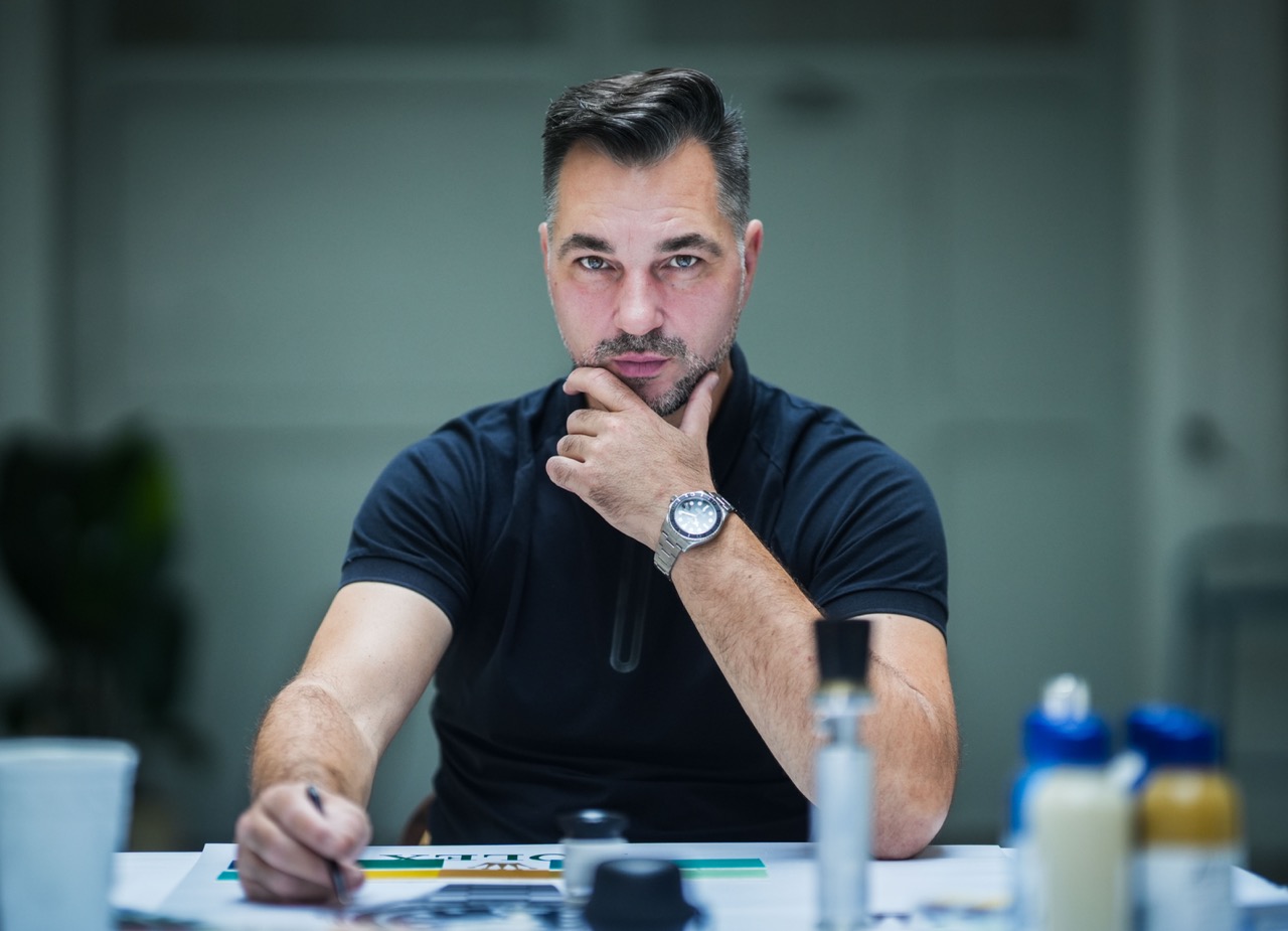 Künstler TANK sitzt am Tisch, analysiert Entwürfe und Farbabstimmungen für das geplante Rolex SailGP Mural.