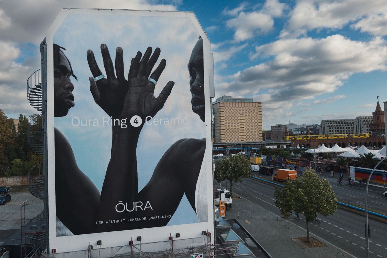 Seitenansicht des Murals am East Side Hotel mit Blick auf die Berliner Straßen und vorbeifahrende U-Bahn.