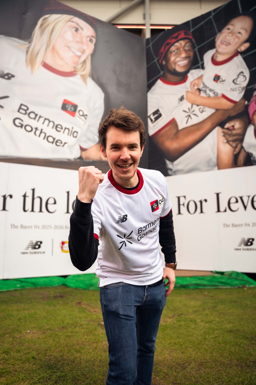 Fan im neuen Bayer-04-Leverkusen-Trikot posiert vor der Installation mit emotionalem Supporter-Motiv.