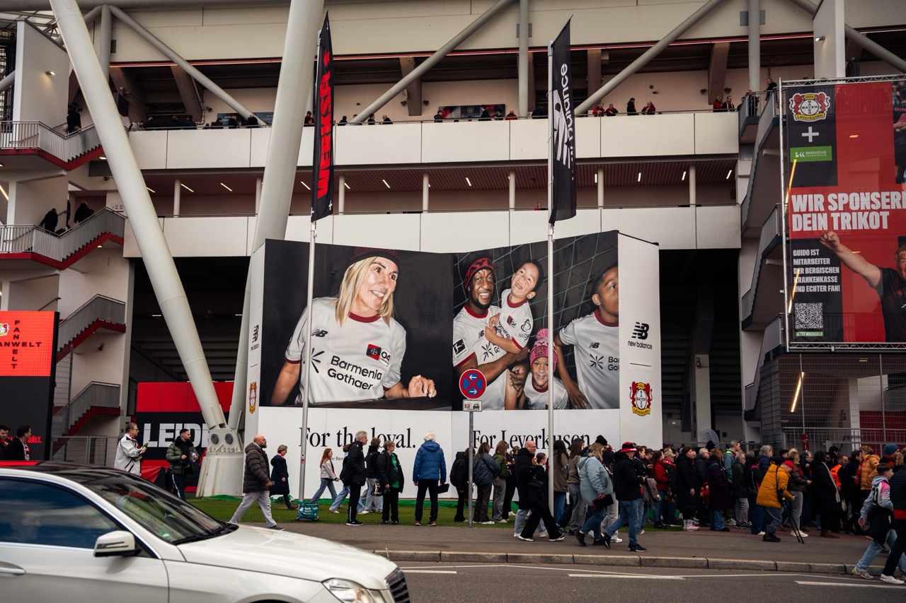 Gesamtansicht der fertigen Installation vor dem Stadion von Bayer 04 Leverkusen mit wartenden Fans und Branding von New Balance.