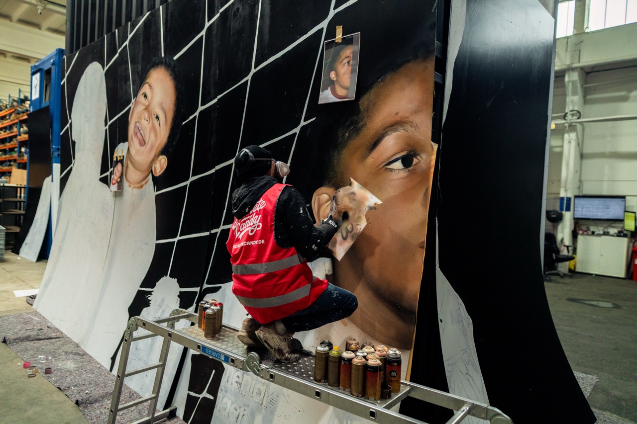 Studioaufnahme während der Entstehung des Murals mit angeheftetem Referenzmaterial und schrittweise aufgebauten Portraitflächen.