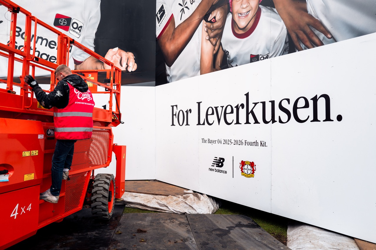 Künstler auf Hebebühne bei der finalen Bearbeitung der Muralinstallation mit Branding von New Balance und Bayer 04 Leverkusen.