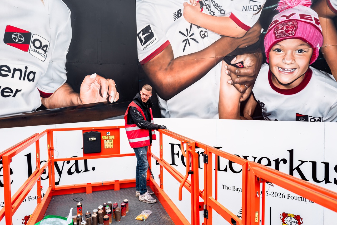Detailaufnahme der großformatigen Installation mit fotorealistischen Portraits und handgemalten Fanmotiven.