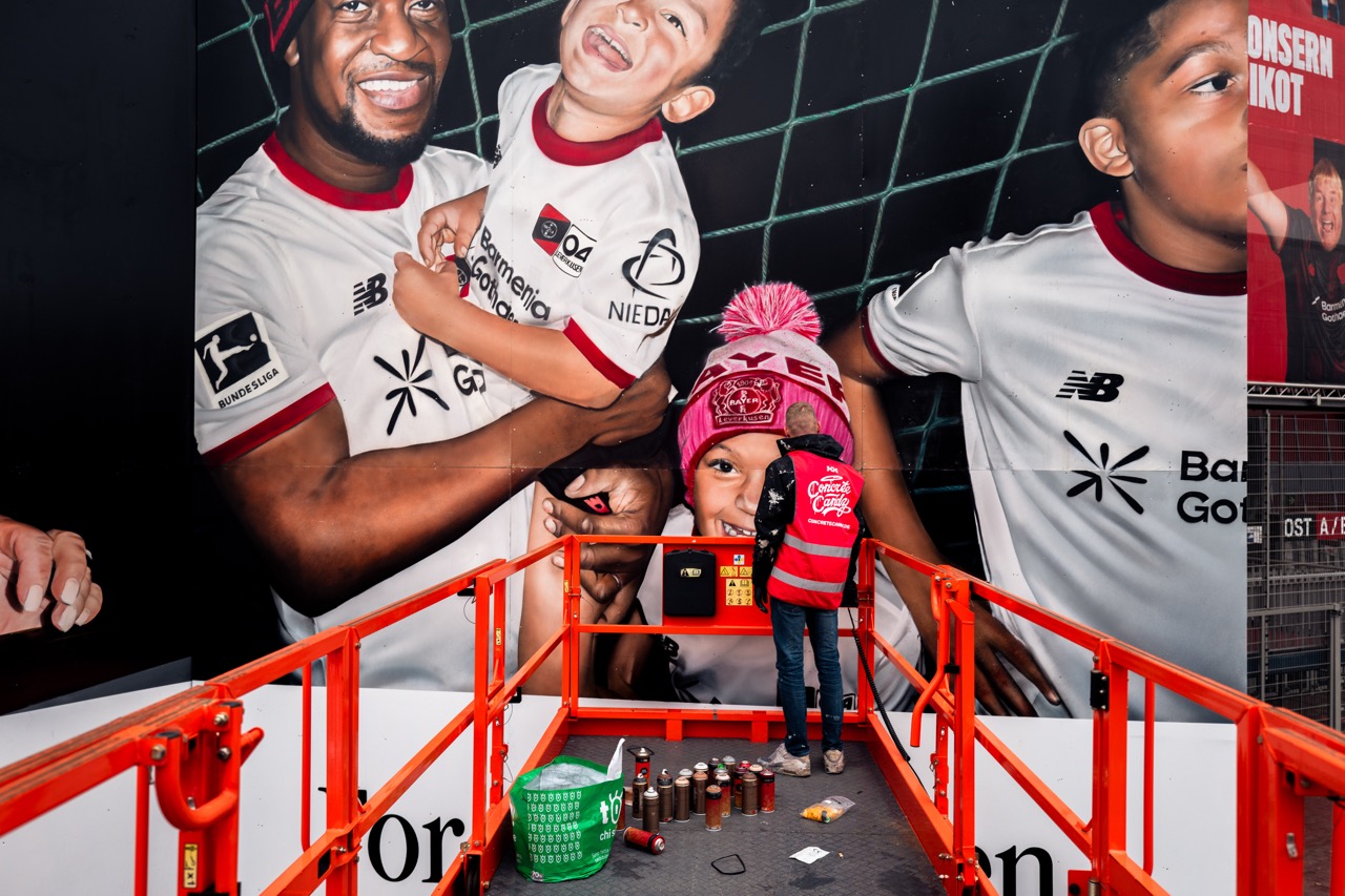 Künstler arbeitet an der finalen Ausarbeitung des Murals auf einer Hebebühne vor dem Stadion.