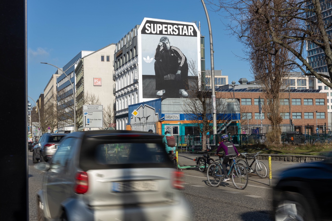 adidas Originals Mural mit Lamine Yamal an einer Berliner Hausfassade, aufgenommen vor vorbeifahrenden Autos und Radfahrer*innen.