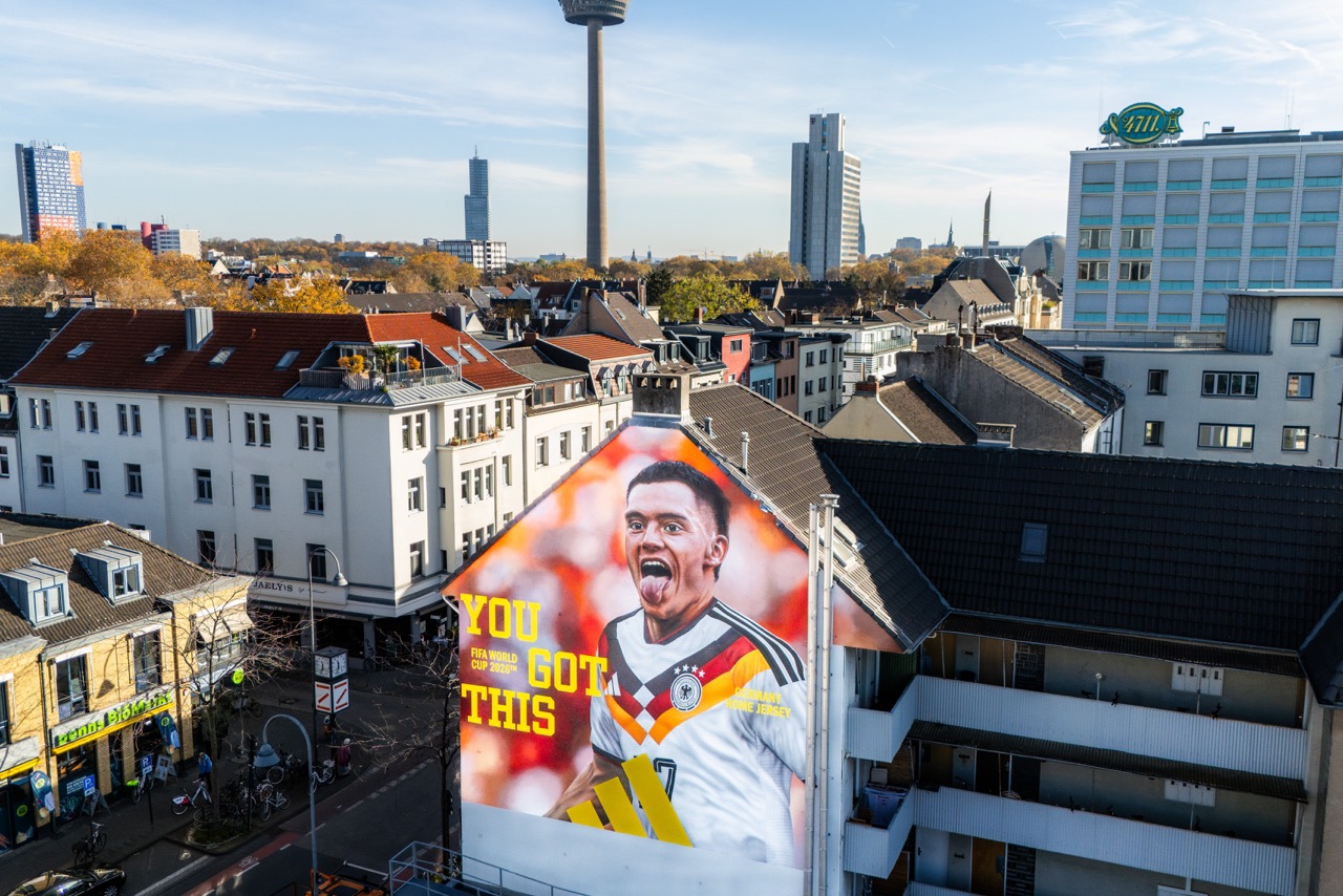 Drohnenaufnahme des fertigen Florian-Wirtz-Murals im neuen DFB Heimtrikot an einer Hausfassade auf der Venloer Straße in Köln-Ehrenfeld.