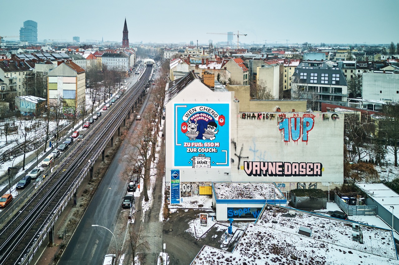 Drohnenaufnahme des WOLT-Murals an der Skalitzer Straße mit Hochbahntrasse, Berliner Altbauten und weitem Blick über Kreuzberg.