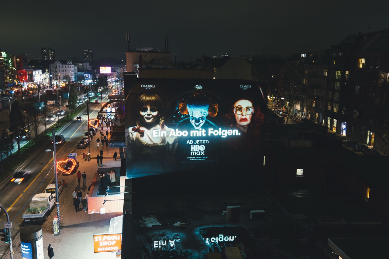 Großformatiges HBO-Max-Mural auf St. Pauli bei Nacht mit Blick über die beleuchtete Reeperbahn und vorbeifahrenden Autos.