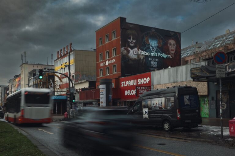 Großformatiges HBO-Max-Mural „Ein Abo mit Folgen“ an einer Gebäudefassade auf der Hamburger Reeperbahn bei dunklem Winterhimmel und vorbeiziehendem Verkehr.