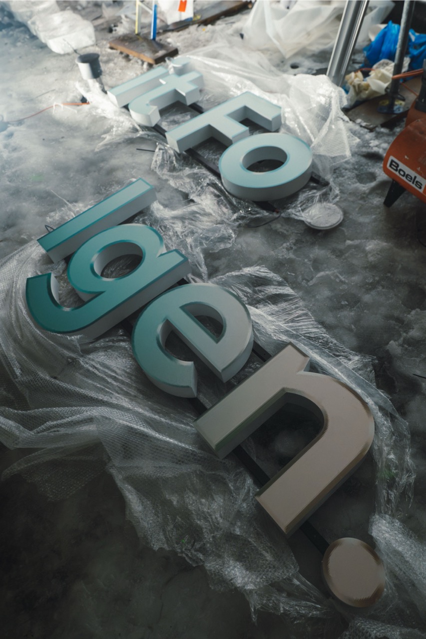 Leuchtende 3D-Buchstaben für den Kampagnenclaim „Ein Abo mit Folgen“ liegen auf einer vereisten Baustellenfläche bereit zur Montage.