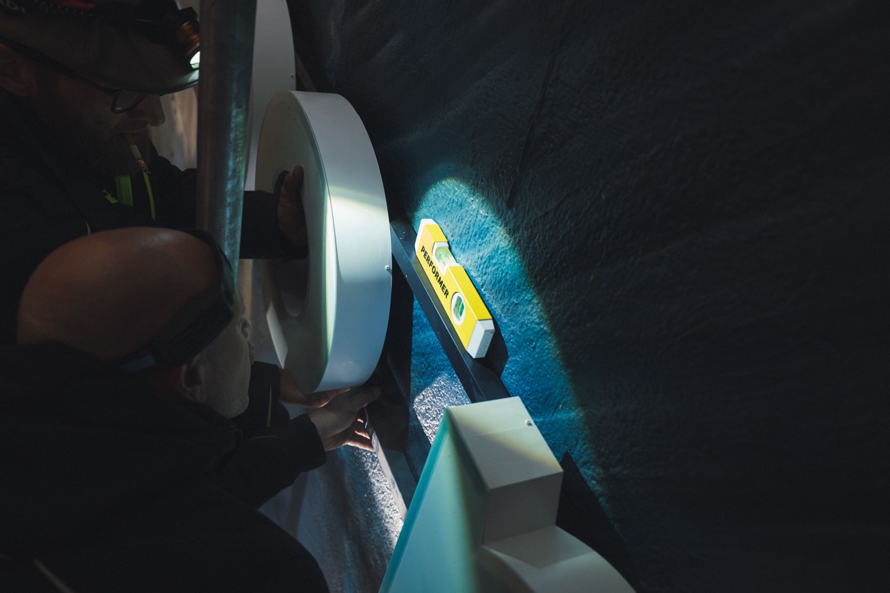 Montage eines beleuchteten 3D-Buchstabens auf der Fassadenwand des HBO-Max-Murals mithilfe von Wasserwaage und Montageprofil.