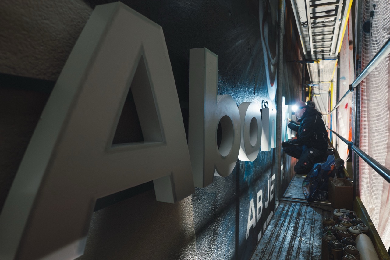 Beleuchtete 3D-Buchstaben des Claims „Ein Abo mit Folgen“ werden auf dem fertigen Mural installiert.