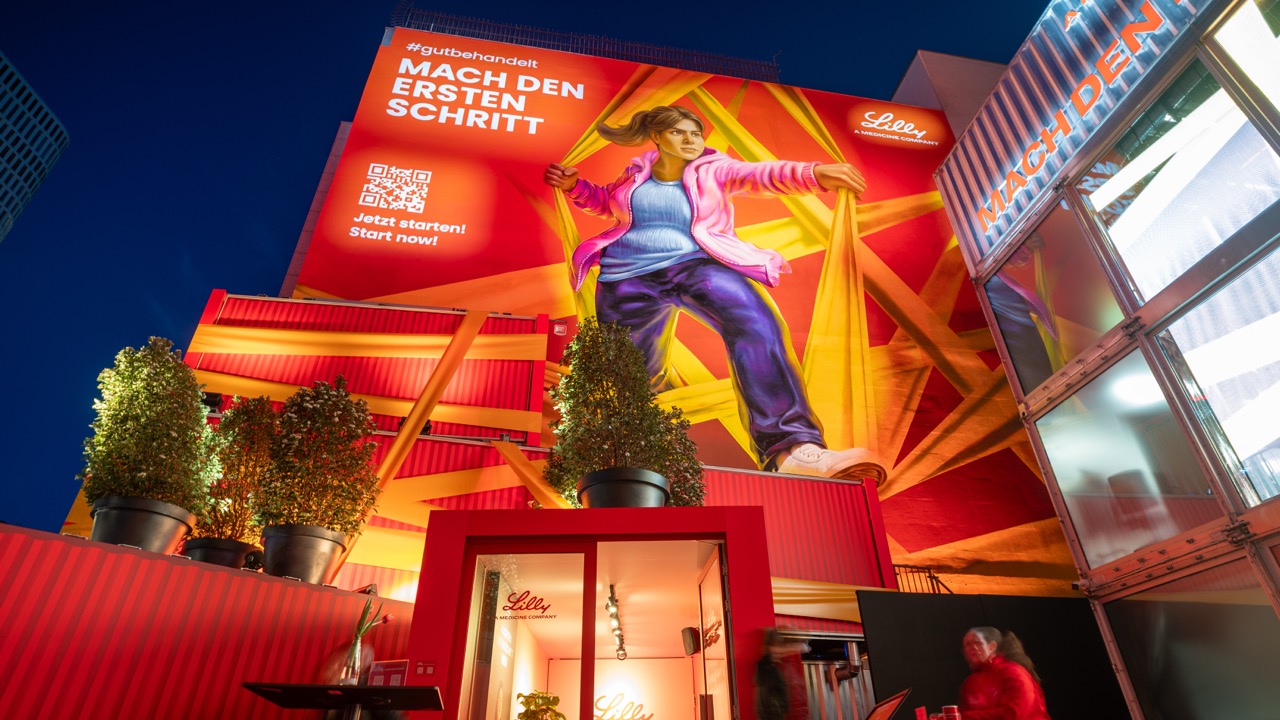 Nachtaufnahme des Lilly Murals mit beleuchteter Containerinstallation und räumlicher Inszenierung am ehemaligen The Space am Berliner Ku’damm.