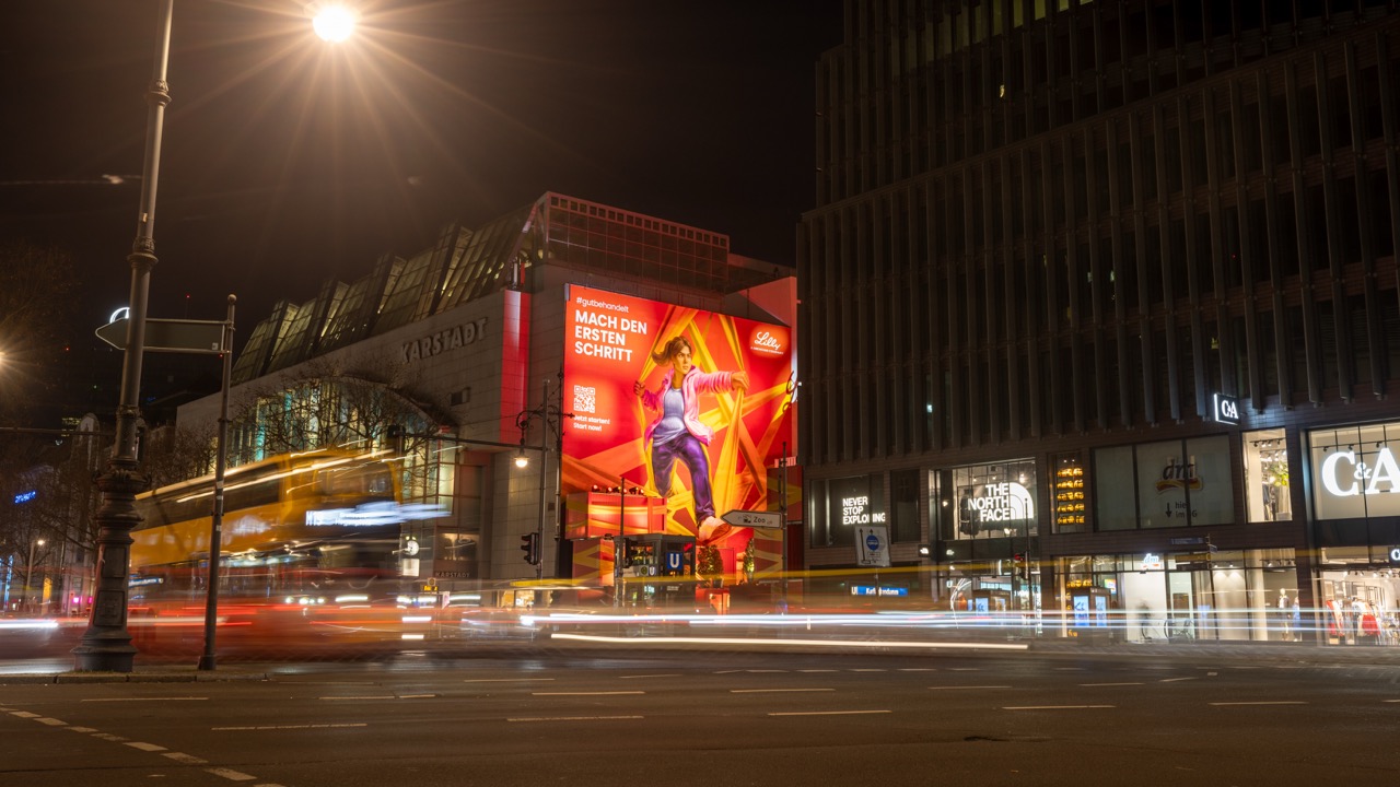 Großformatiges Lilly Mural mit vorbeiziehendem Verkehr und Langzeitbelichtung am Berliner Ku’damm.