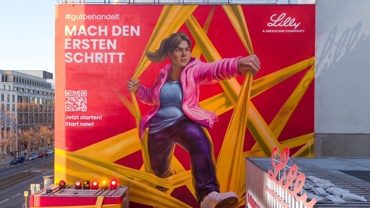 Detailaufnahme des großformatigen Lilly Murals mit figurativer Illustration und grafischen Elementen auf der Fassadenfläche.