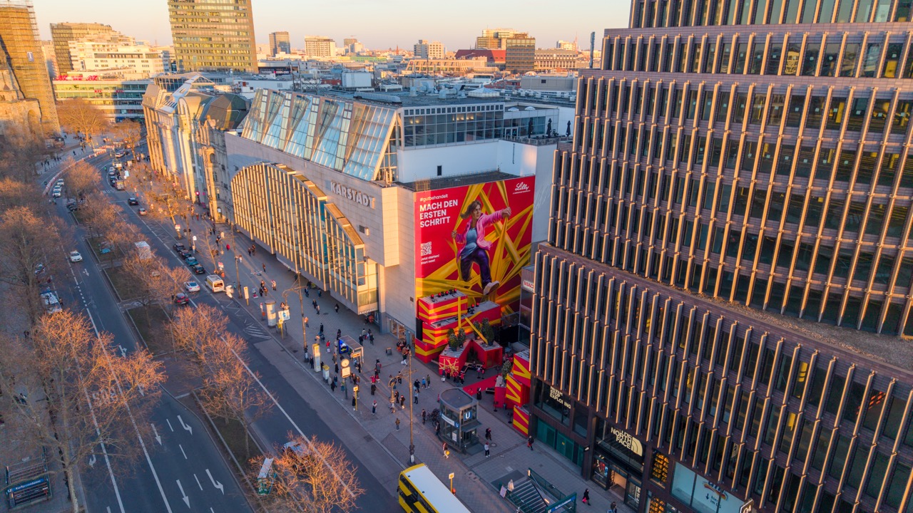 Drohnenaufnahme des Berliner Ku’damms mit vollständigem Lilly Takeover am ehemaligen The Space und Blick über die umliegende Stadt.