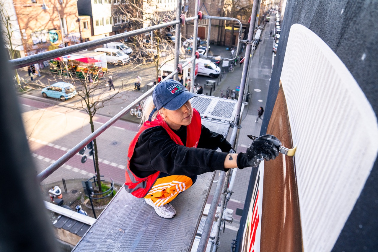 Artist arbeitet auf dem Gerüst an den Details des Nutella MOTION MURAL® in urbaner Umgebung.