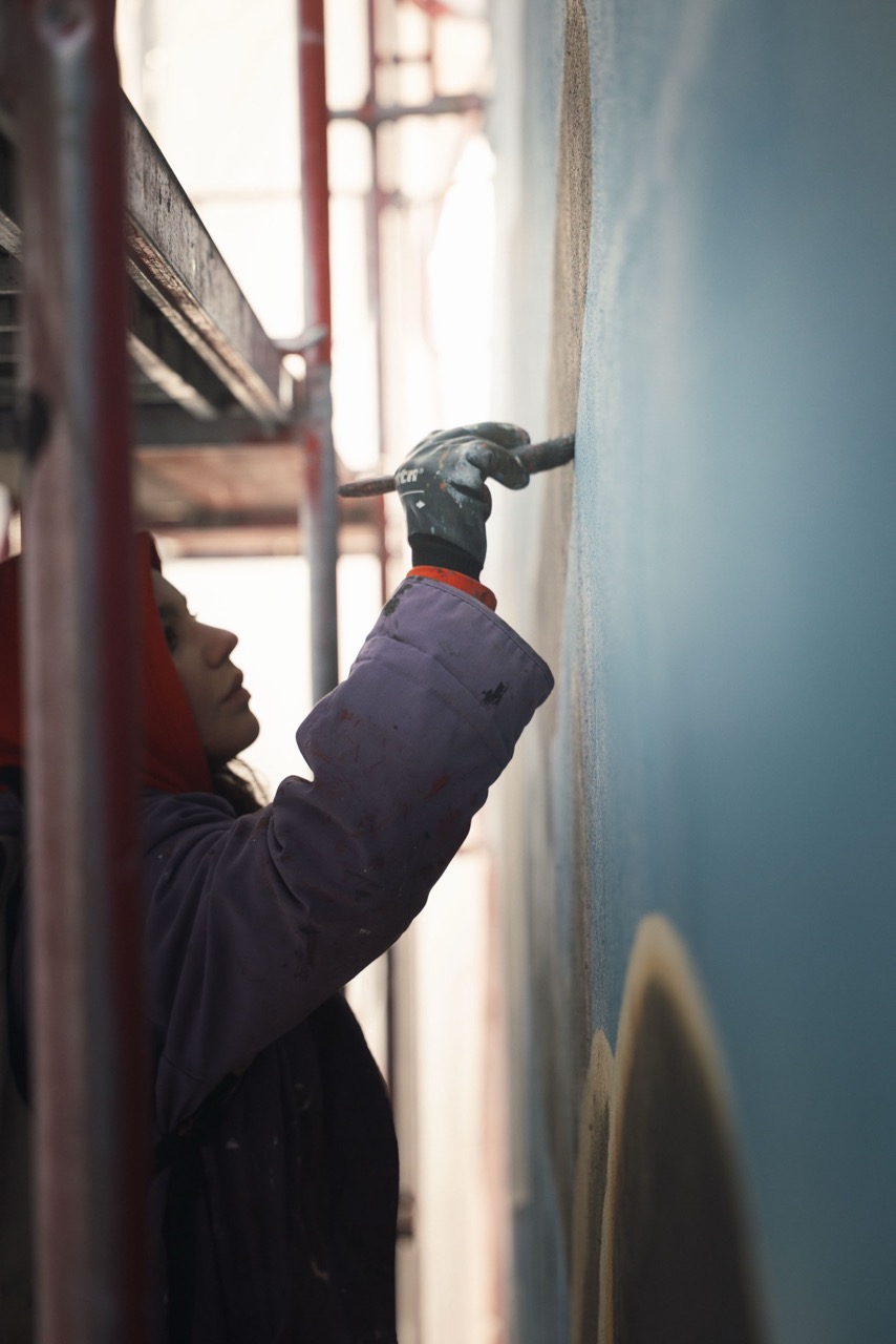 Künstlerin malt feine Übergänge und Schattierungen auf der Fassade des Ralph-Lauren-Murals in Berlin.