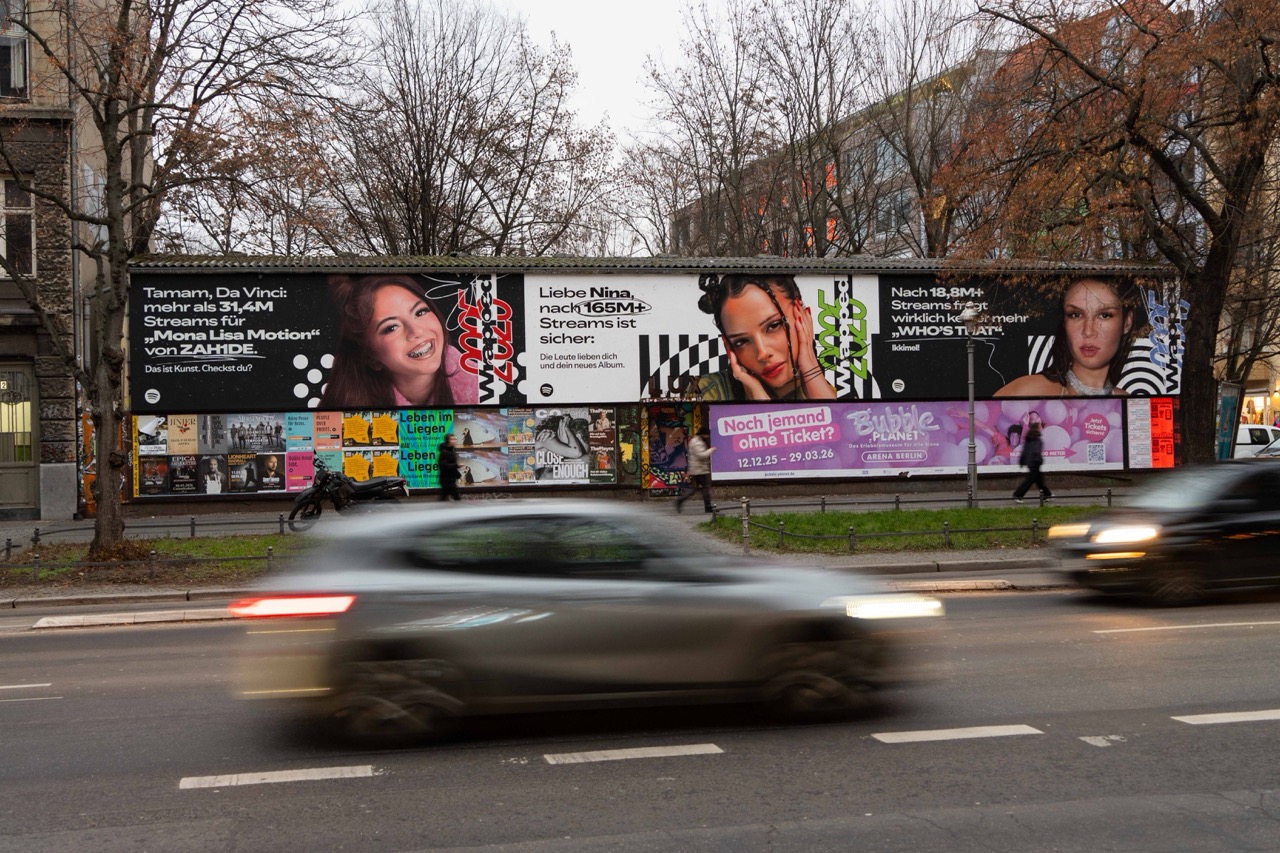 Lange Spotify Wrapped Fassadeninstallation mit mehreren Künstler*innen entlang einer Berliner Hauptstraße bei fließendem Verkehr.