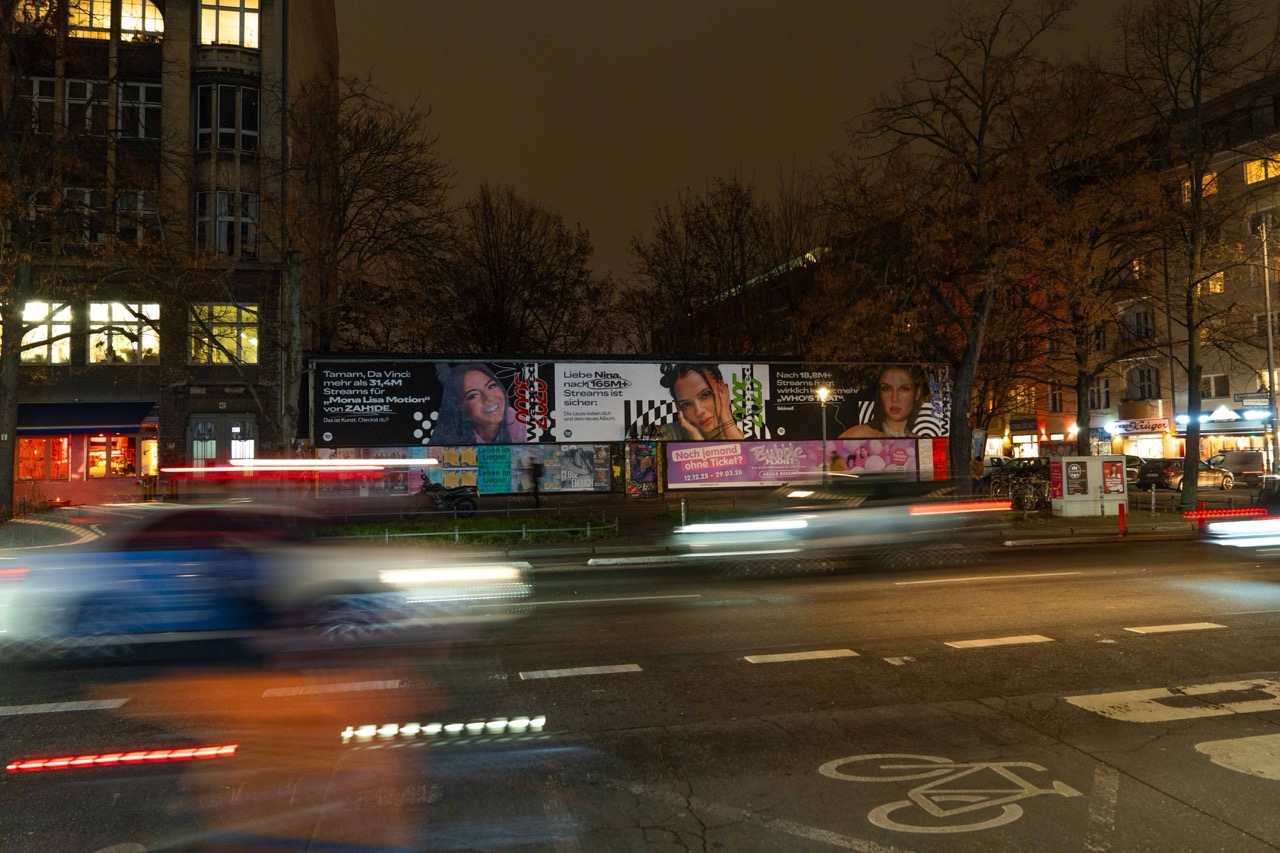 Weitwinkelaufnahme der beleuchteten Spotify Wrapped Installation in Berlin mit vorbeifahrenden Autos und Lichtspuren.