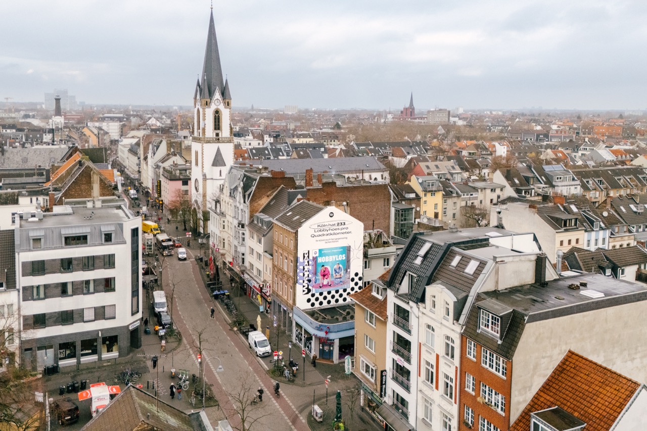 Großformatiges Spotify Podcast Mural für „Hobbylos“ an einer Häuserfassade entlang der Venloer Straße in Köln.