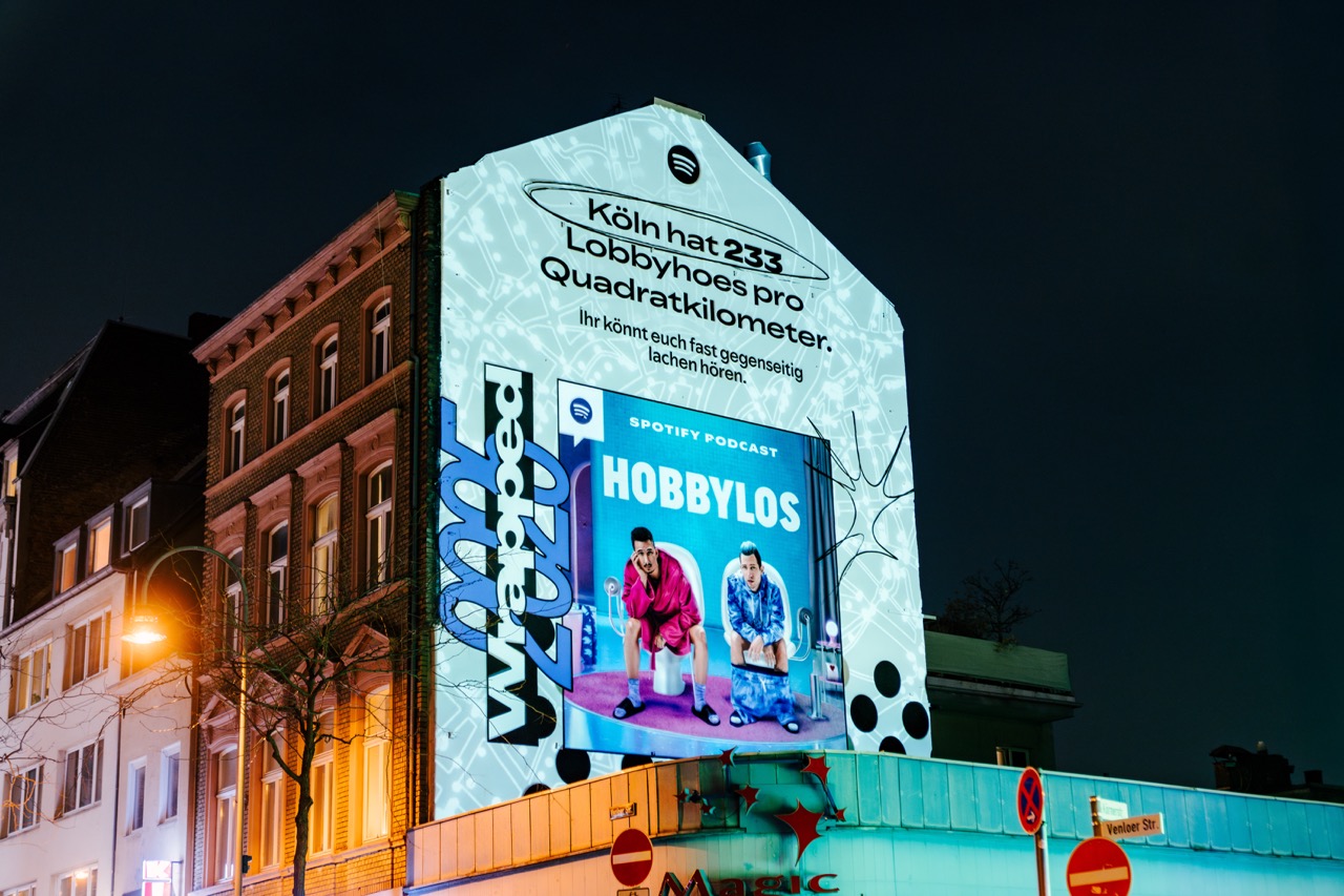 Spotify Wrapped Mural mit „Hobbylos“-Motiv an einer Straßenecke in Köln bei bewölktem Wetter.