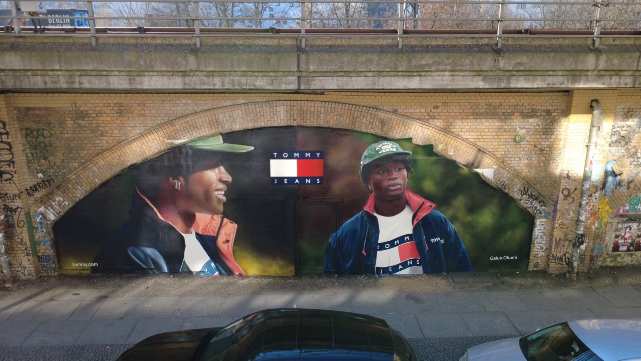 Tommy Hilfiger Mural mit Gaius Okami unter den S-Bahn-Bögen der Diercksenstraße in Berlin-Mitte, aufgenommen aus erhöhter Perspektive.