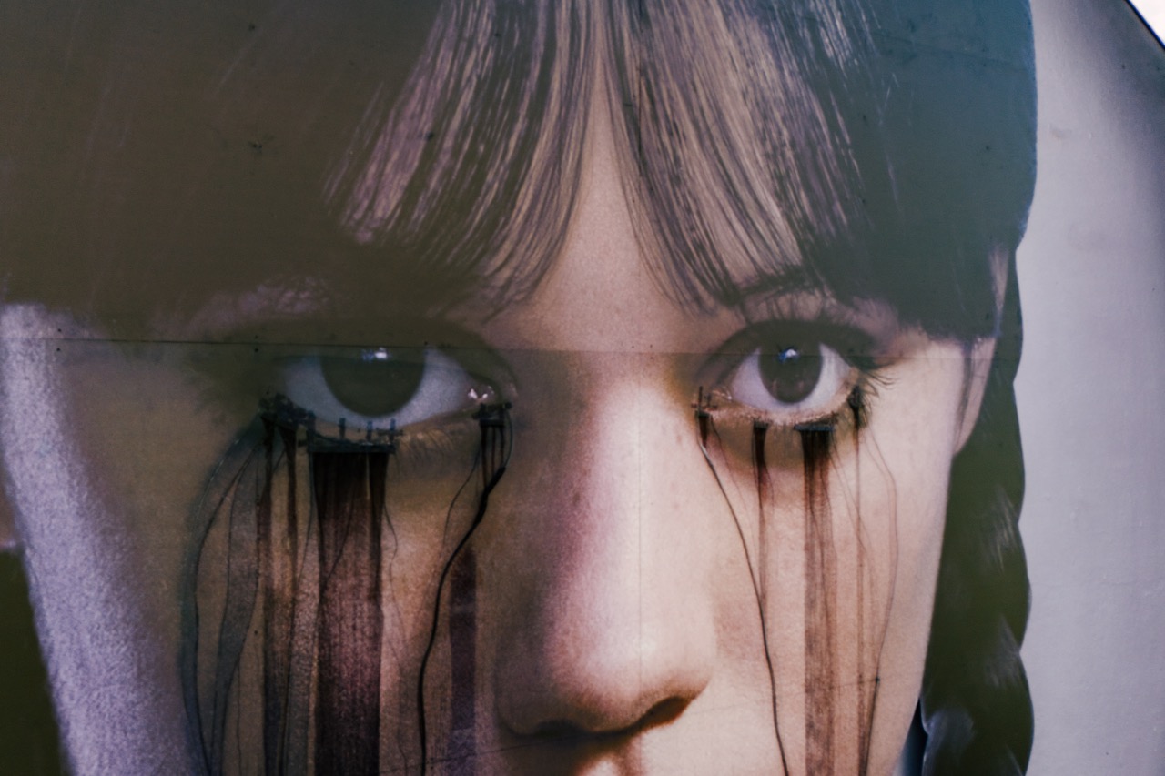 Nahaufnahme des Crying-Effekts am Netflix „Wednesday“-Mural mit schwarzen Flüssigkeitsspuren unter den Augen.