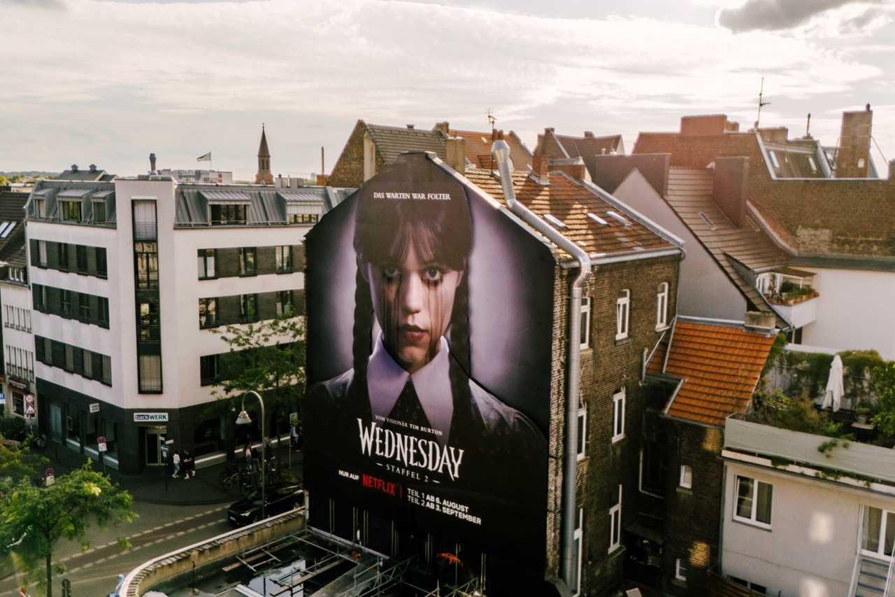 Fertige großformatige Netflix „Wednesday“-Installation auf einer Hausfassade in Köln aus der Vogelperspektive.