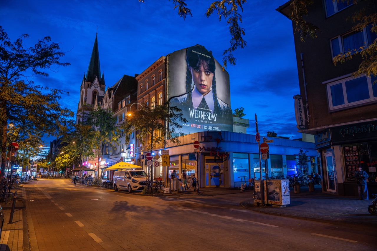 Netflix „Wednesday“-Installation bei Nacht in Köln mit beleuchteter Fassade und dunkler Atmosphäre.