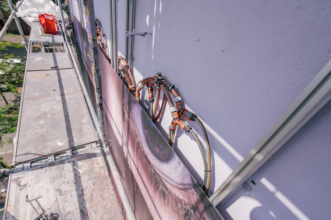 Schlauchsystem hinter den bedruckten Fassadenplatten zur Steuerung des Crying-Effekts beim Netflix „Wednesday“-Mural.